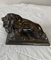 Left-front view of bronze lion paperweight showing overall form and patina