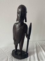 Front view of ebony Maasai warrior statue showing spear and draped garment