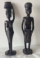 Front view of male and female ebony statues standing on bases