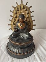 Front view of seated Buddha statue showing halo, pedestal and patina details