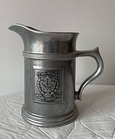 Full profile of pewter pitcher with crest visible