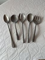 Front view of five hammered metal serving utensils arranged side by side