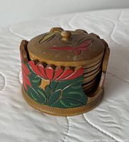 Coaster holder filled with coasters, lid on top showing painted floral and butterfly decoration