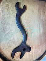 Full view of curved cast iron plow wrench showing both open ends and square socket