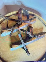 Top view of both wooden skates showing straps, buckles, and steel blades