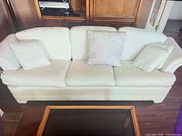 front view of ivory sofa with three seat cushions and pillows