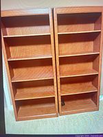 Front view of both walnut bookcases showing five shelves each