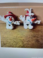 Front view of both rubber Schneemann mascot figurines