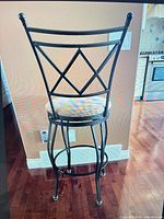 Rear view of single stool showing black metal frame and upholstered seat