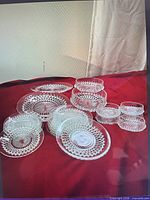 Group view of cut glass plates and bowls on red cloth