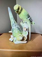 Front view showing two green budgies and floral base
