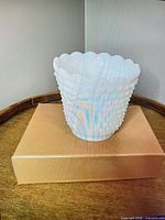 front view of small white hobnail milk glass vase on wood tray