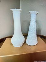 Front view of both white milk glass vases showing shapes and ribbed texture