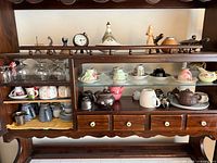 Overview of entire cabinet showing teapots, cups, mugs, glassware and figurines