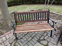 Full view of wood and cast-iron garden bench on brick patio