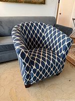 Front angled view of blue patterned barrel chair showing upholstery and legs