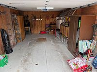 Wide view of garage showing ladders, cabinets, garden tools and supplies