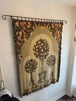 Full view of tapestry hanging on rod, shows design and fringe