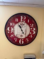 Full view of large red and white Paris wall clock on wall