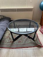 Front angled view of round glass coffee table showing glass top and metal frame