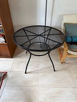 Overall view of round black metal mesh patio table