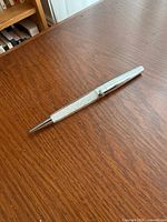 Full view of silver-tone Swarovski ballpoint pen on wood surface