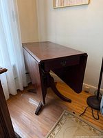 Table with one leaf down showing drawer and pedestal base