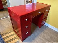 three-quarter front view of red desk showing drawers and overall form