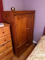 Front view of solid wood armoire beside dresser