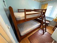 Full view of assembled wood bunk bed with ladder and both mattresses