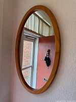 Front view of oval wood-framed mirror hung on wall