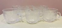 Full set of eight clear Arcoroc cups on surface