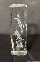 Front view of clear glass block showing laser-etched dolphins and ocean scene