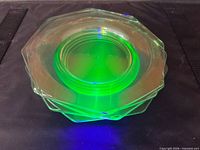 stack of four green uranium glass octagonal plates glowing under UV