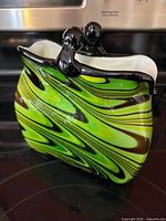 Front view of purse-shaped green swirled glass vase