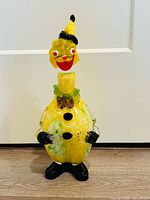 Full frontal view of yellow glass clown decanter showing overall form and colors