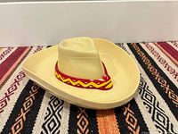 Cowboy hat-shaped beige plastic chip and dip bowl with red/yellow trim on patterned surface