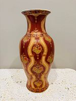 Full view of burgundy porcelain vase with gold detailing