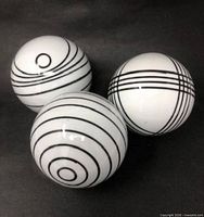 Three large white porcelain carpet balls with black line patterns