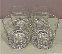 Four clear crystal lowball glasses viewed from side showing starburst bases