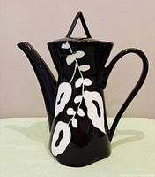 Full view of porcelain coffee pot showing shape, color, lid and spout