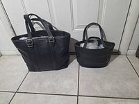 Front view of both black leather Coach purses side by side