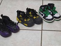 All three pairs of children’s Nike sneakers aligned on floor