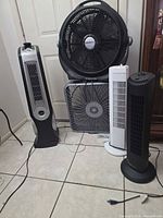 Five fans together showing variety: Lasko tower, floor fan, box fan, two slim tower fans