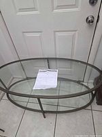 Full view of oval glass coffee table with metal frame and included instruction sheet