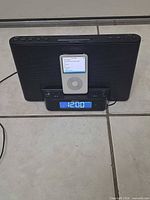 Front view of iPod seated in Sony dock showing speaker grille and clock display