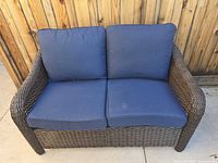 Front view of brown wicker loveseat with blue cushions