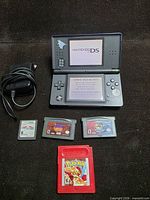 Console, charger and four game cartridges displayed