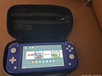 Front view of powered-on blue Nintendo Switch Lite inside carry case showing home screen