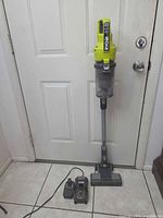 Full view of Ryobi stick vacuum standing upright with battery attached